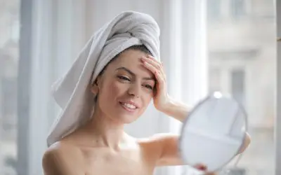Selective focus portrait photo of smiling woman with a towel on head looking in the mirror